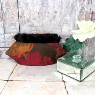 Red and gold brocade evening clutch with a black rosette trim.