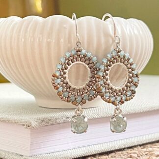 Pale blue beaded earrings with a crystal drop displayed on a white ceramic trinket dish