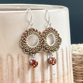 Circle beaded earrings in Autumn shades with silver earring hooks displayed on a ceramic pot