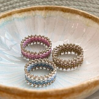Beaded rings in pink, blue and olive green, in a ceramic trinket dish