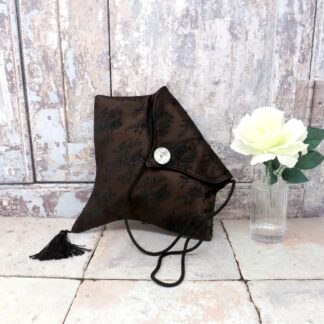 A gothic inspired evening bag in brown satin overlaid with black lace, and with a black tassel trim.