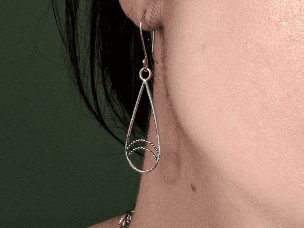 Silver teardrop earrings with twisted wire detailin being worn by a dark-haired model.