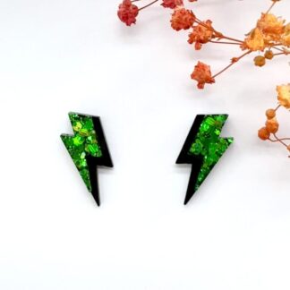 A pair of glittery green and black accent lightning bolt hypoallergenic stud earrings on a white background.