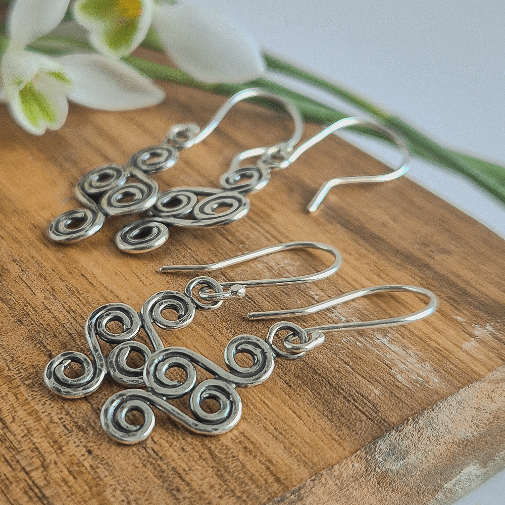 Side view of two pairs of double-ended silver spiral earrings.
