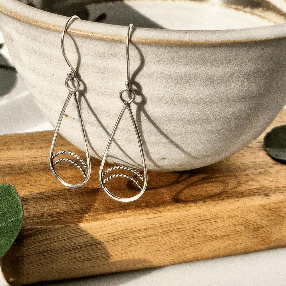 Sterling silver teardrop earrings hanging off the edge of a bowl