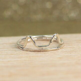 A set of Sterling silver cat stacking rings are shown stacked on a table.