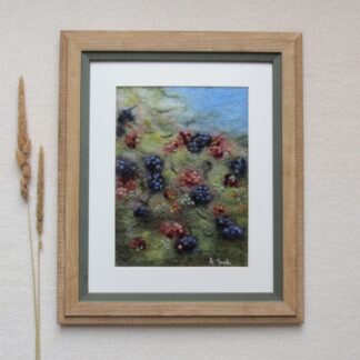 Wool felted blackberry brambles in mixed greens with a blue sky. The berries are red with pink highlights and the black with blue and purple highlights.