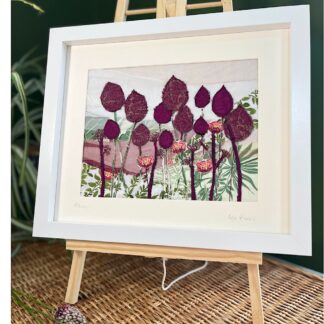 Framed textile artwork showing burgundy alliums reaching for the sky. Leaning on a picture stand