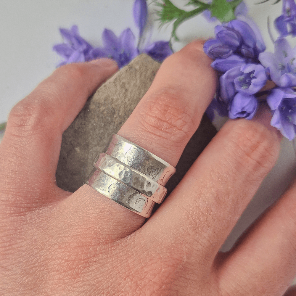 Handmade sterling silver spinner ring being worn on the ring finger of a mocel's hand.