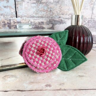 A cerise floral textile and felt brooch.