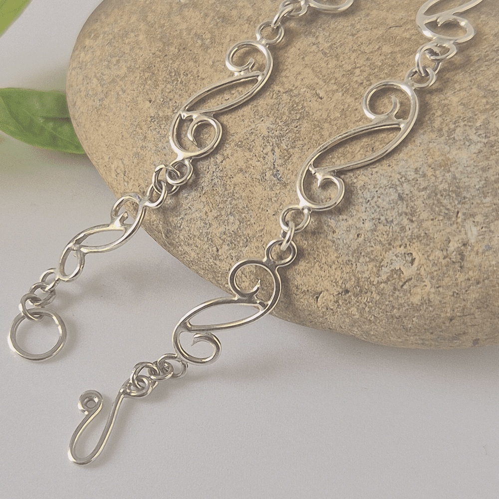 Closeup shot showing the hook clasp on the spiral bracelet resting on a stone.