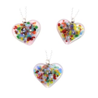 Three handmade heart-shaped pendants made of clear glass. Each pendant contains colorful, confetti-like pieces and shiny dichroic glass fragments embedded inside, creating a vibrant and eye-catching design. The pendants are suspended from delicate silver chains.