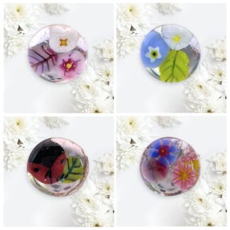 Four intricately designed handmade glass rings featuring vibrant flowers and intricate patterns, surrounded by white chrysanthemums.