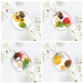 Four colorful handmade glass pendants featuring floral and animal designs, surrounded by white chrysanthemums.