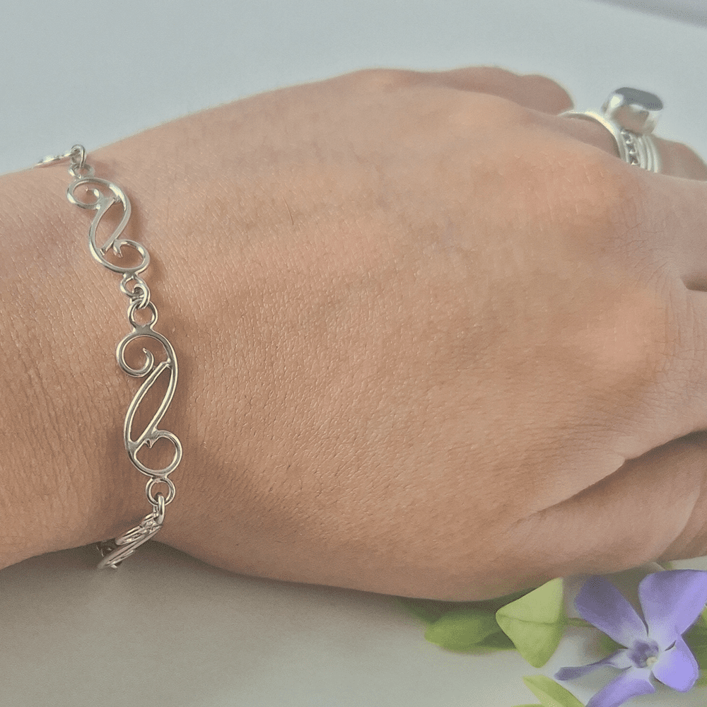 Silver spiral wave braceet being worn on a model's wrist.