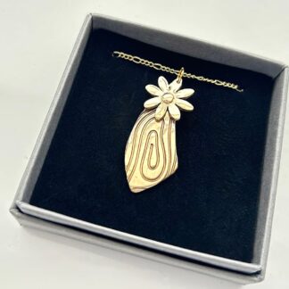 Bronze clay handcrafted wood effect pendant with a gold plated chain. Displayed on black velvet background.