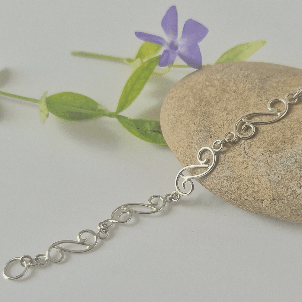 Sterling silver bracelet made from double-ended spirals resting on a stone.