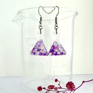 A pair of conical flask earrings with purple holographic glitter and three bubble detail hang from hypoallergenic surgical steel ear hooks.