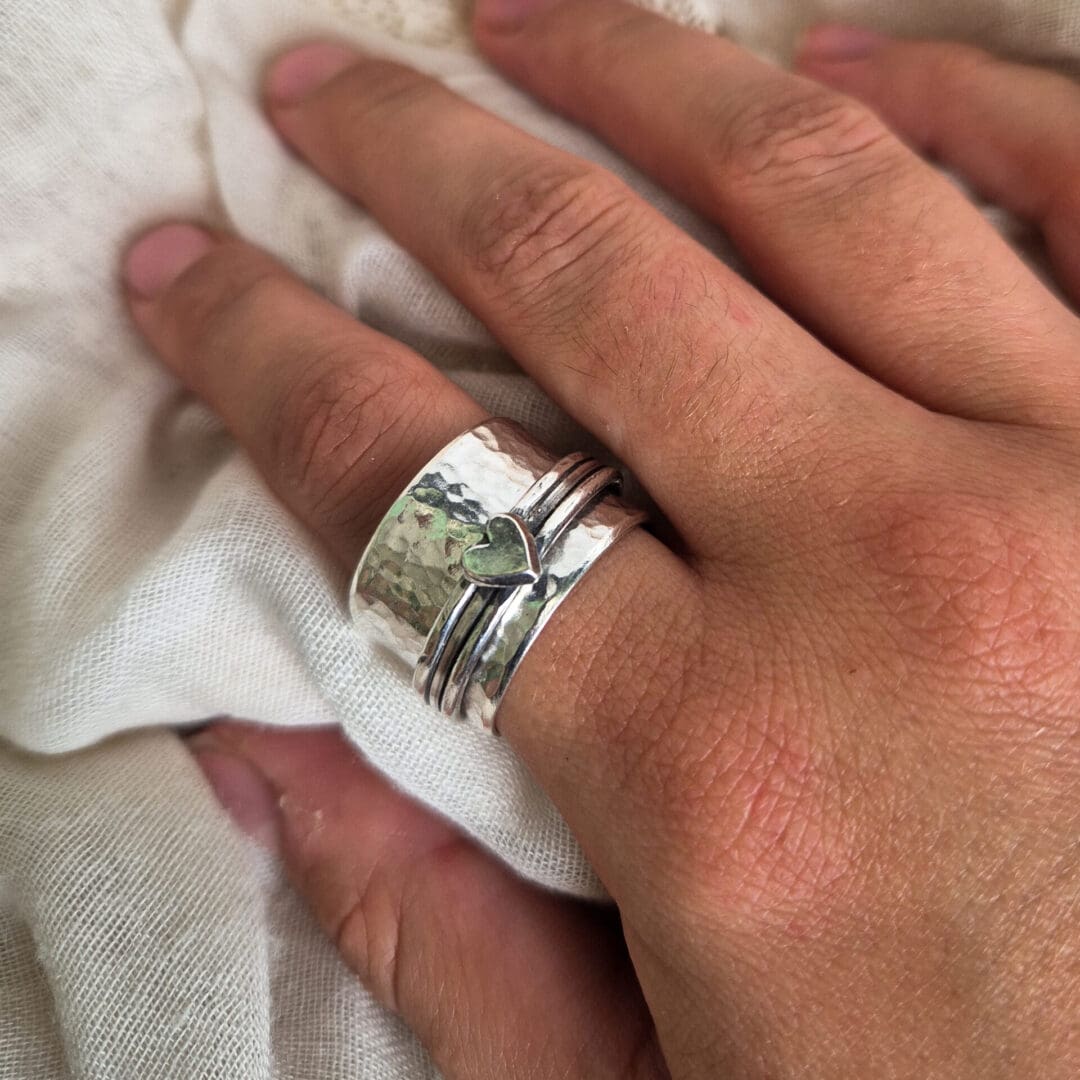 Chunky hammered sterling silver ring with heart being worn on a model's index finger.