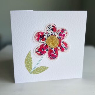 Red applique flower on greetings card standing on table
