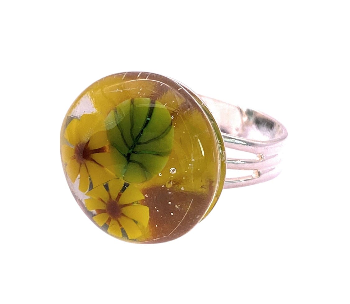 A bright yellow sunflower ring featuring Millefiori flowers and leaves, set on a polished silver band, capturing a vibrant natural aesthetic.