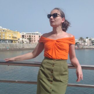 woman wearing bardot style top with twist detail at front, in orange colours