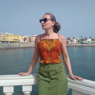 woman wearing orange batik print cami top and green button down skirt