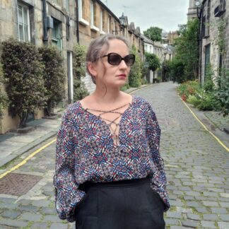 woman dressed in blue laced up blouse standing in Circuc Lane in Edinburgh
