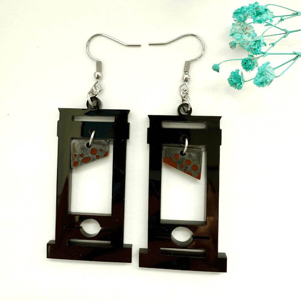 Handmade black resin guillotine earrings with swinging blood-red blade detail, gothic statement jewellery for Halloween and alternative fashion.