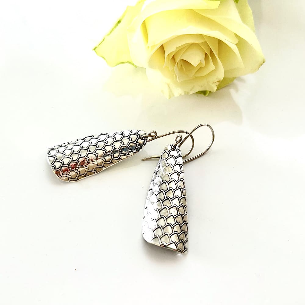 A pair of handmade large fine silver clay drop,earrings with a textured pattern. They have sterling silver ear wires and are displayed on a white background.