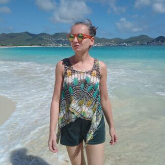 woman wearing colourful tank top and shorts, walking on a beach