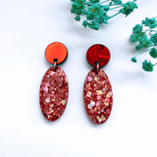 A pair of handmade pink glitter statement earrings inspired by Glinda from Wicked, with sparkling oval resin drops and golden mirror stud tops, displayed on Copper Magpie Designs card.