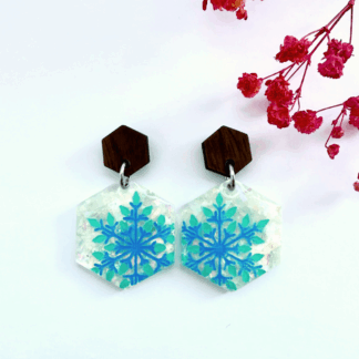 Handmade hexagon resin earrings with shimmering icy background and vibrant blue snowflake design, topped with walnut wood hexagon studs, winter-inspired jewellery for seasonal style