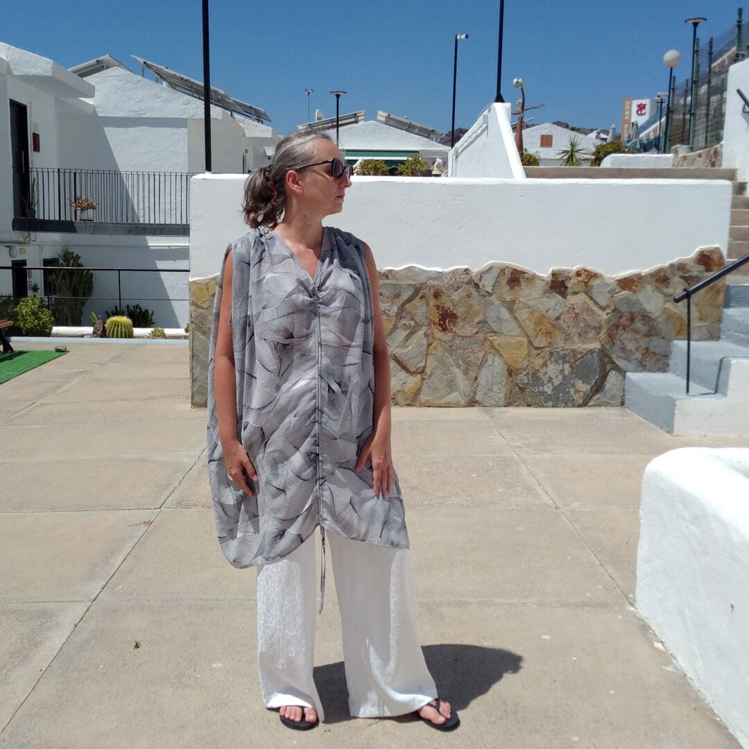 woman wearing sleeveless tunic dress and white trousers