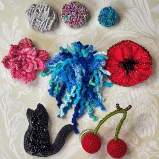 A mix of contemporary, modern embroidered brooches in various designs.