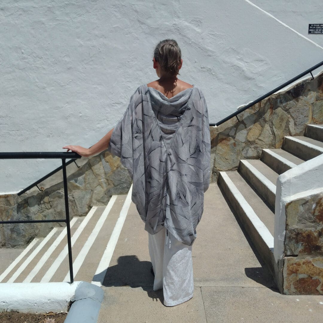 woman wearing loose kimono top in monochrome print and white trousers