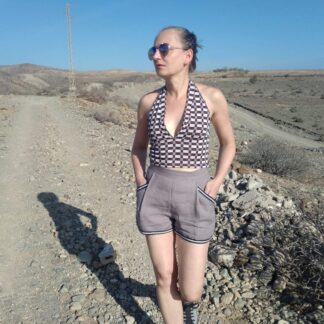 woman wearing gey linen shorts and 60s style halter top walking in a desert