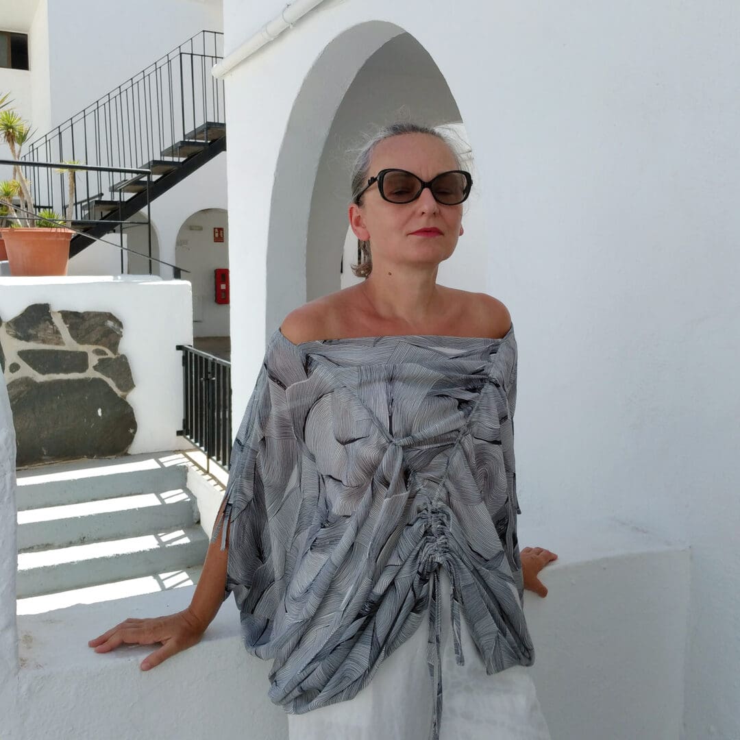 woman in a off-shoulder top sitting on a wall
