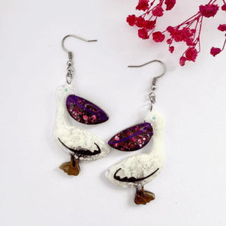 Quirky pelican drop earrings in shimmering midnight purple glitter beaks.