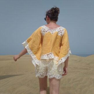 woman walking in sand dunes, dressed in yellow kimono top with white lace and white lace shorts