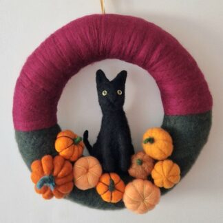 felted black cat amongst pumpkins on a burgundy and green wreath