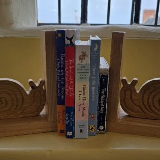 Handmade oak snail bookends holding children’s books, crafted with traditional box joints and finished in natural beeswax.
