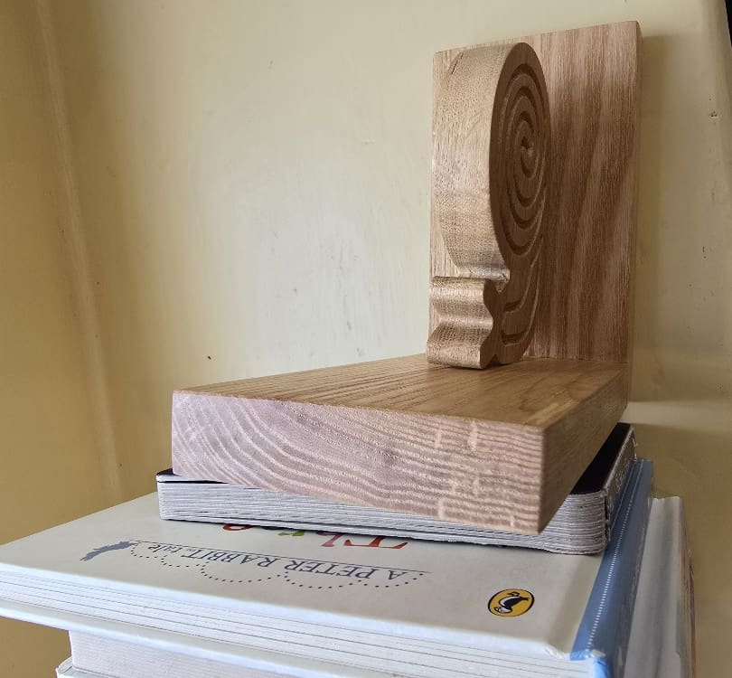 Handmade oak snail bookends holding children’s books, crafted with traditional box joints and finished in natural beeswax.