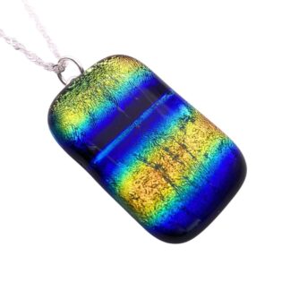 A dichroic glass pendant with vibrant blue, green, and yellow stripes, featuring a gleaming, iridescent finish. It hangs from a silver chain, creating a bold and dynamic look.