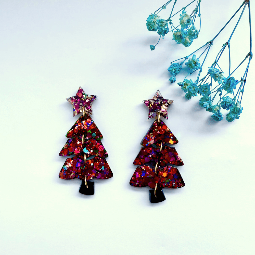Handmade glitter Christmas tree earrings with star toppers on a white background.