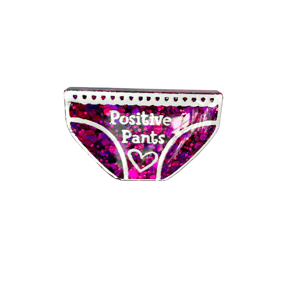 Close-up of Positive Pants resin pin badge showing glitter detail