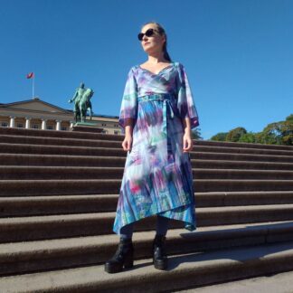 woman dressed in blue wrap dress standing on the steps leading to The Royal Palace in Oslo, Norway