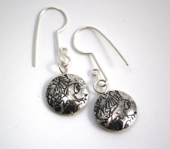 round silver drop earrings with a motif of a flying owl embossed onto the surface of each side