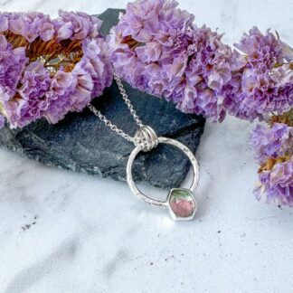 Pink and Green Watermelon Tourmaline Gemstone in a hexagon shape. Set in a circle of silver which has a hammered texture. Suspended on a silver necklace.