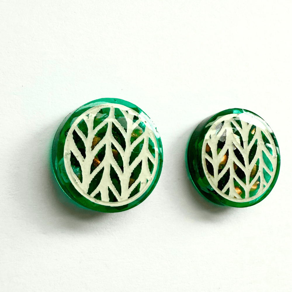 Left teal knitted-effect stud earring with holographic glitter background – detailed close-up view.